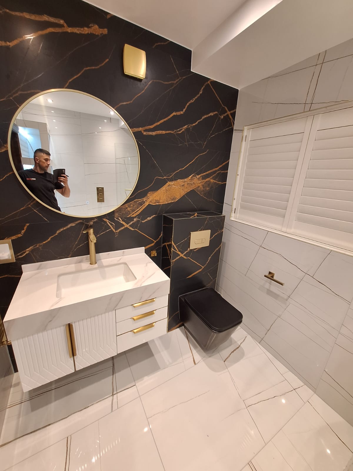 Black square wall-hung WC with brushed brass flush plate on Portoro marble