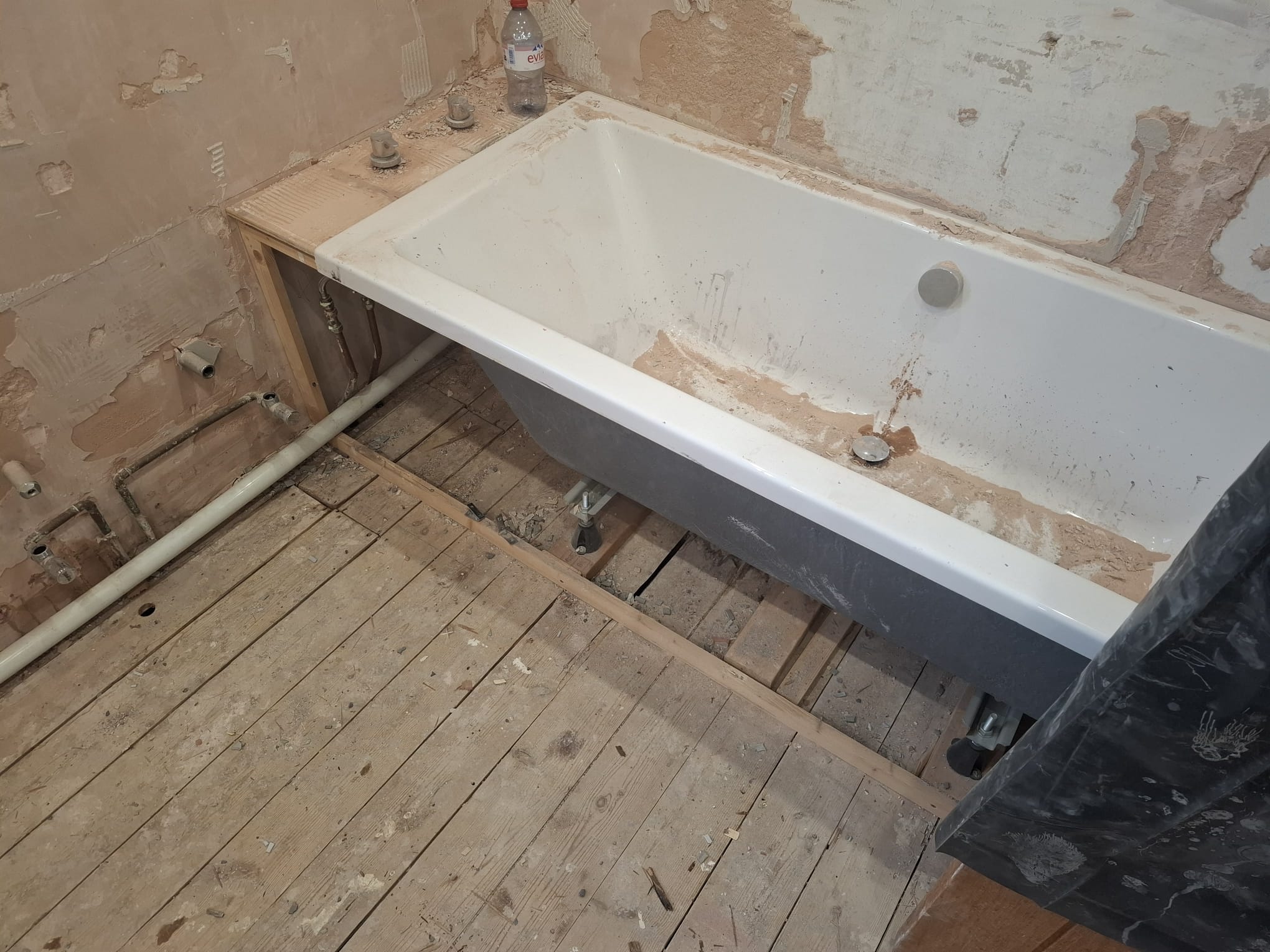 Before renovation, old bathtub and stripped bathroom walls